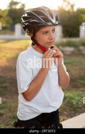 Ragazza adolescente che indossa il casco per ciclismo all'aperto durante il giro in bicicletta. Sport all'aperto. Stile di vita attivo. Foto Stock