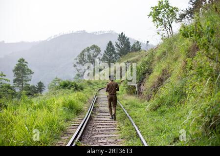 Ella, Sri Lanka, 5 agosto 2018: Un poliziotto locale che cammina sui binari del treno Foto Stock