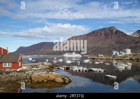 Ilulissat, Groenlandia, 6 luglio 2018: Una grande nave da crociera e barche da pesca ancorate nel porto di Qeqertarsuaq Foto Stock