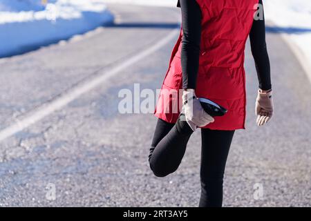 Coltivare donne che si allungano su strade invernali Foto Stock