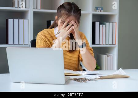 Donna stressata che cerca di gestire documenti finanziari, avendo problemi a trovare soldi per pagare bollette o prestiti Foto Stock