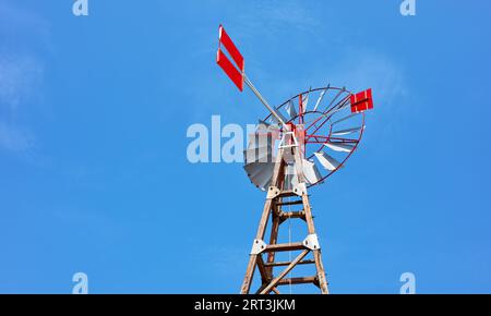 Una vecchia pompa a vento contro il cielo blu. Foto Stock
