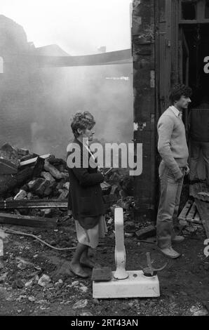 Toxteth Riots 1980s UK. La mattina dopo la notte dei disordini, le bilance di un fruttivendolo giacciono abbandonate fuori da un negozio bruciato, mentre i residenti guardano con incredulità a ciò che è successo al loro quartiere. Toxteth, Liverpool, Inghilterra circa luglio 1981. HOMER SYKES Foto Stock