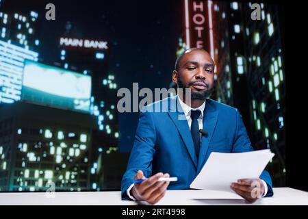 Anchorman che ospita uno show televisivo in tarda serata e presenta scandali delle celebrità, discutendo degli ultimi argomenti importanti in sala stampa. Presentatore di media afroamericano che trasmette notizie quotidiane su rete televisiva. Foto Stock