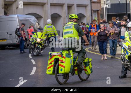 LONDRA - 22 aprile 2023: Risposta di protesta di Londra: Un ciclista paramedico e una motocicletta della polizia partecipano alla marcia XR, pronta a fornire assistenza di emergenza Foto Stock