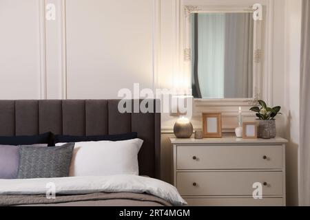 Elegante interno della camera da letto con letto grande e comodo e cassettiera Foto Stock