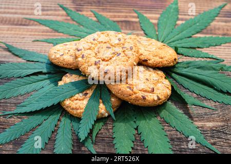 Biscotti con gocce di cioccolato alla cannabis con una foglia di marijuana sulla griglia su un tavolo marrone di legno. Gusto dolce e delizioso. Spazio per il testo. Concetto di cooki Foto Stock