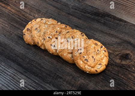 biscotti rotondi sottili con molti semi di sesamo, deliziosi biscotti con semi di sesamo bianco su tavola di legno ed elettrodomestici da cucina in legno Foto Stock