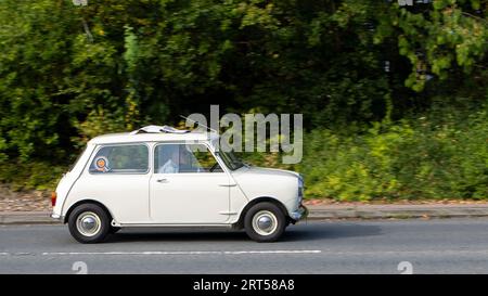 Milton Keynes, Regno Unito-10 settembre 2023: 1960 BMC MkI Mini bianco, Rover Mini, Austin Seven, auto che viaggia su una strada inglese. Foto Stock