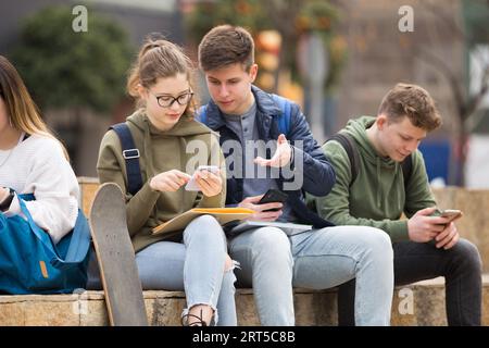 Gruppo di ragazzi che utilizzano gli smartphone all'aperto Foto Stock