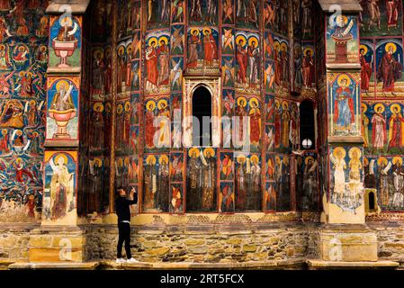 Selfie a treppiede di fronte agli affreschi dipinti del monastero di Moldovița nella remota regione della Bucovina, nel nord-est della Romania, un sito UNSECO WH Foto Stock