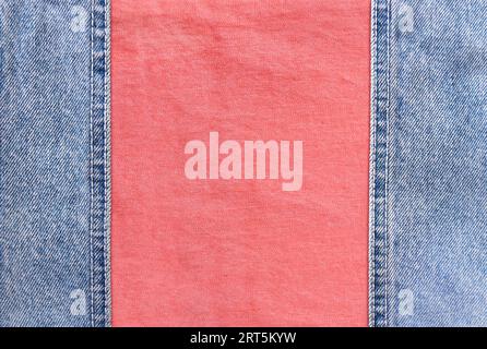 Bordi in denim blu con cuciture e texture in cotone corallo. Tessuto jeans in denim di colore azzurro e rosa. Spazio di copia per il testo Foto Stock