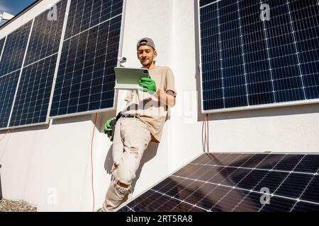 Tecnico con un tablet digitale su un tetto con centrale a energia solare Foto Stock