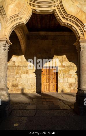 Arco e colonna del chiostro dell'Università di Salamanca con la sua ombra sulla parete del corridoio dalla luce del sole serale che incornicia una o Foto Stock