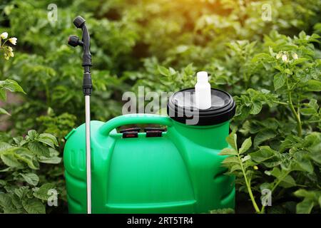 Piccola bottiglia bianca di pesticida, erbicida per proteggere le piante da malattie e parassiti con supporti mock up su spruzzatore contenitore su sfondo verde naturale del giardino. Lavori agricoli stagionali. Foto Stock