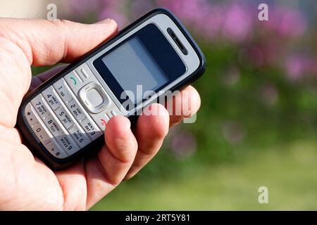 Un vecchio telefono cellulare a pulsante in una mano Foto Stock