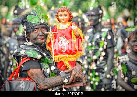 Vecchia donna che tiene un figur di Santo Nino al festival ATI Atihan. Foto Stock