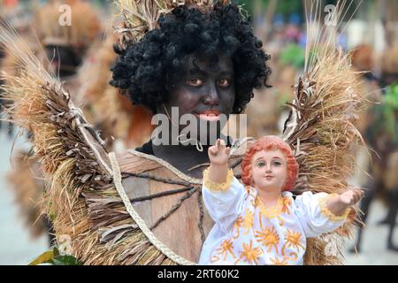 Uomo transessuale che tiene un figur di Santo Nino al festival ATI Atihan, Ibajay. Foto Stock