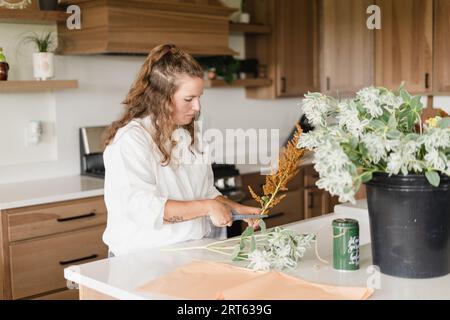 Un fiorista che taglia fiori da sistemare in un bouquet di fiori tagliati Foto Stock