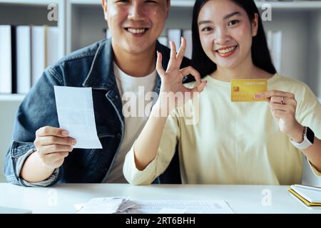 Giovane coppia fiduciosa nell'investimento, nella pianificazione finanziaria insieme, donna che mostra il segno OK l'uomo mostra la calcolatrice Foto Stock
