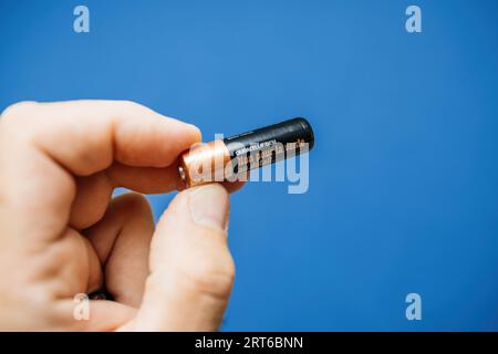 Parigi, Francia - 12 luglio 2023: Una mano maschile regge una batteria AAA Duracell, contrastando brillantemente su uno sfondo blu freddo. Foto Stock