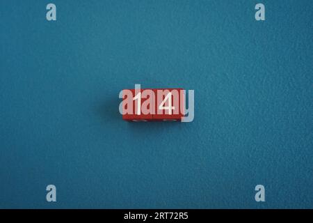 Cubi Viva Magenta in legno con il numero 14 su sfondo blu vista dall'alto. Concetto di data o ora. Numeri bianchi 14 Foto Stock