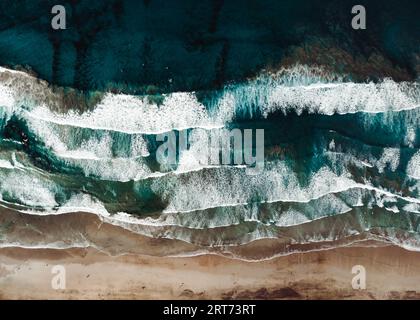 Vista dall'alto dal drone della spiaggia di sabbia gialla con oceano e onde. Spiaggia con molti surfisti e persone nelle giornate di sole dall'alto. Foto Stock