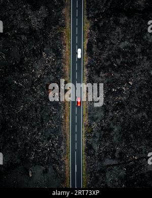 Foto verticale della strada con due auto con sfocatura del movimento dall'alto con drone - foto notturna a Lanzarote. Strada dritta tra le lavas sul si Foto Stock