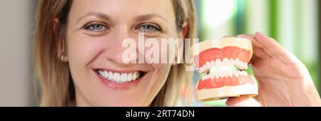 Donna sorridente dentista tenendo modello di mascelle nelle sue mani primo piano. Foto Stock