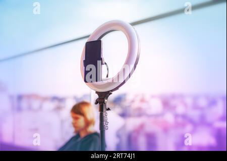 Selfie LED con illuminatore anulare con smartphone. Apparecchiature per blogging. Sfondo esterno. Dispositivo informativo portatile. Foto Stock