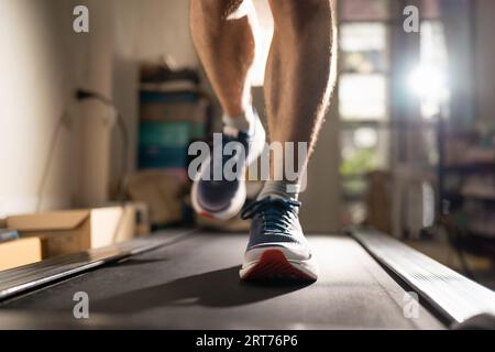 Uomini che corrono su un tapis roulant a casa Foto Stock