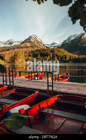 Barche rosse nel porto delimitate in talpa di legno sul lago Strbske pleso in alta Tatra, Slovacchia in autunno. Splendida e colorata alba sul lago con colazione Foto Stock