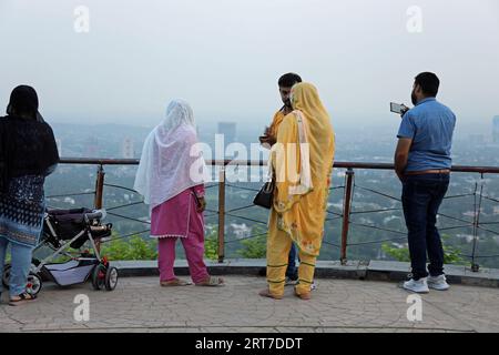 I turisti che guardano in basso la città di Islamabad da un punto panoramico di Daman-e-Koh sulle colline di Margalla Foto Stock