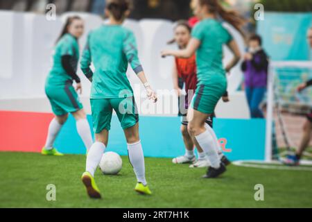 Partita di calcio femminile in strada all'aperto su un prato artificiale di astroerba sintetica, le ragazze giocano a calcio su un campo di campo, le giovani donne partecipano a un calcio Foto Stock