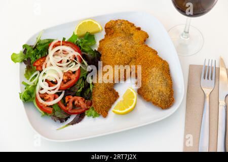 Milanesa appena cucinata con insalata servita al piatto Foto Stock