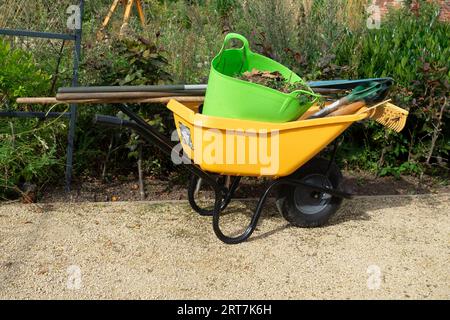 Carriola gialla dei giardinieri nel giardino murato di Kirkleatham con materiali e attrezzi per piantare Foto Stock