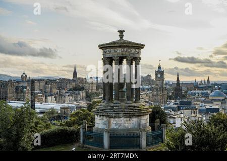 Paesaggio urbano di Edimburgo al tramonto. Dugald Stewart Monument in primo piano, edifici storici e guglie della cattedrale dietro. Ideale per viaggi e tradizioni scozzesi. Foto Stock