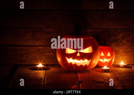 Tre lanterne in zucca di Halloween e candele accese su sfondo di legno scuro Foto Stock