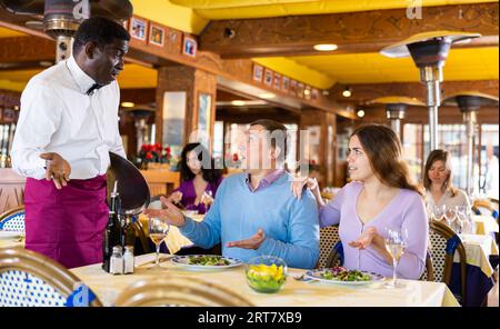 Gli ospiti insoddisfatti sono in conflitto con il cameriere afroamericano del ristorante Foto Stock