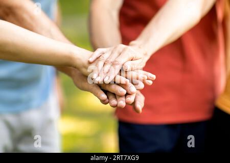Concetto di unità. Gruppo di persone mature che uniscono le mani insieme mentre si trovano all'aperto Foto Stock