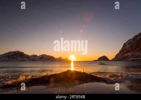 La famosa spiaggia di sabbia nei pressi di Haukland durante il tramonto sul Lofoten isole in Norvegia in chiaro giorno d'inverno con neve-rivestito montagne e cielo blu Foto Stock