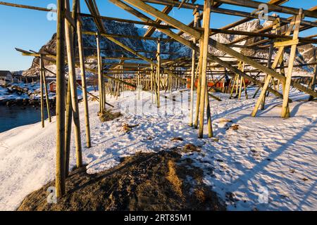 Scaffali di legno vuoti per appendere e asciugare cod per fare Pesce di mare sulle isole Lofoten vicino al villaggio Reine in La Norvegia sulla giornata invernale limpida con il blu Foto Stock