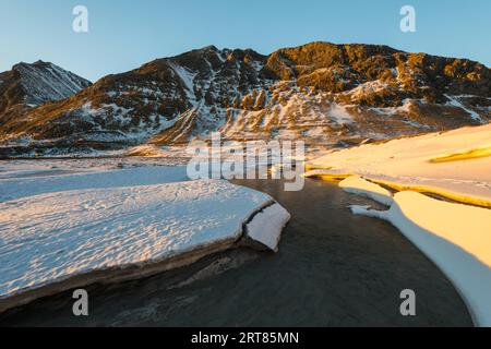 La famosa spiaggia di sabbia nei pressi di Haukland durante il tramonto sul Lofoten isole in Norvegia in chiaro giorno d'inverno con neve-rivestito montagne e cielo blu Foto Stock