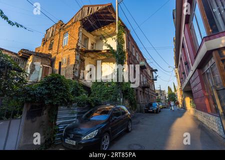 Un edificio residenziale gravemente fatiscente in una strada laterale nella città vecchia di Tbilisi, Georgia. I piani superiori dell'edificio in mattoni sono parzialmente crollati, con travi in legno a vista e muratura che ne evidenziano lo stato di abbandono. Case ristrutturate e fatiscenti si trovano fianco a fianco nella città vecchia, il risultato di decenni di lavori di ristrutturazione trascurati dopo l'era sovietica. Anton Chekhov Street, Zemo Avlabari, Metromsheni, Isani District, Tbilisi, 0144, Georgia Foto Stock