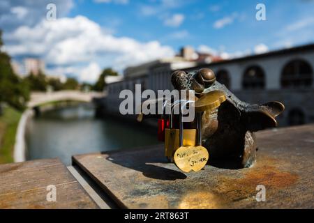 I lucchetti dell'amante bloccati alle figurine sul ponte sopra la Ljubljanica fiume a Lubiana in giornata di sole Foto Stock