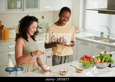 I compagni di stanza erano allegri, bevevano caffè e preparavano la colazione in cucina Foto Stock