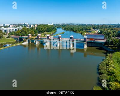 Cracovia, Poalnd. Diga di Dabie sul fiume Vistola con ponte e piccola centrale idroelettrica sulla destra e serranda d'acqua con barca sulla sinistra Foto Stock