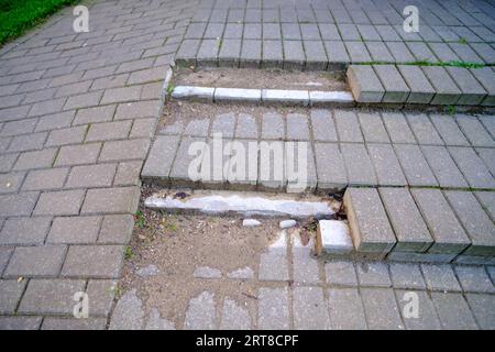 Scalini danneggiati realizzati con lastra di pavimentazione non sicuri per i pedoni. Scalinata rotta. Scala rotta con gradini da lastre grigie. Scarsa qualità di br Foto Stock