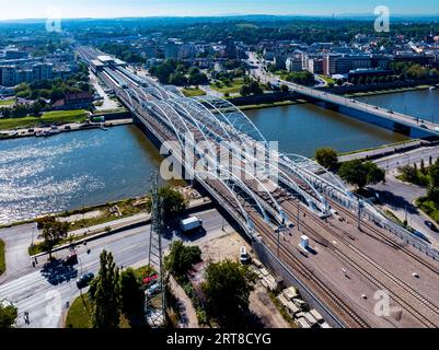 Nuovo ponte ferroviario a tre archi con quattro binari, passerella pedonale e pista ciclabile sul fiume Vistola a Cracovia, Polonia. Vista lontana della nuova Cracovia Zabloci Foto Stock