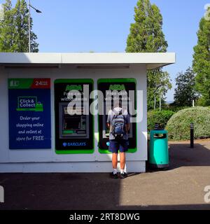 Un uomo al bancomat che prende soldi dal bancomat Foto Stock